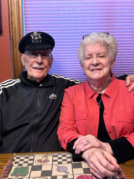 Man with hat sitting next to woman in red jacket