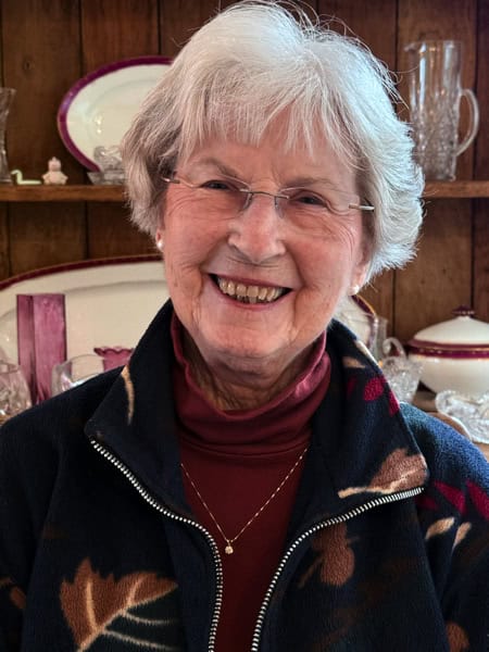 Woman with white hair, glasses, and a pretty smile